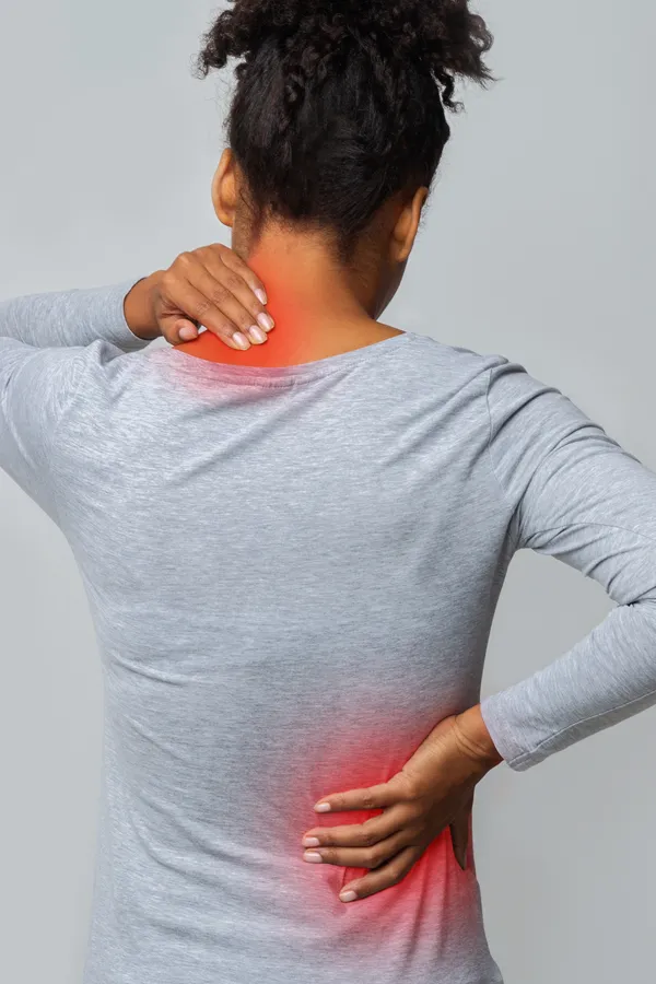 Fibromyalgia-Treatment An image from behind of a woman suffering from Fibromyalgia holding her hands on her neck and lower back. Get fibromyalgia treatment from Delara Tavakoli, M.D. of Tavicare in Chevy Chase.