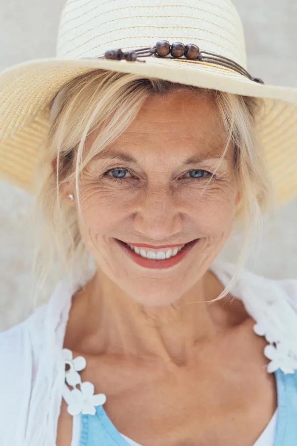 Menopause-Treatment A beautiful, smiling older woman with blonde hair and a sunhat, happy with menopause treatment from Delara Tavakoli, M.D. of Tavicare in Chevy Chase.