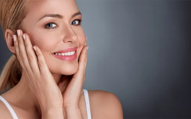 RenaaSculpt-Facial-Tightening-Clinic A woman with glowing skin holds her face. Schedule RenaSculpt Facial Tightening treatment from Delara Tavakoli, M.D. of Tavicare in Chevy Chase.