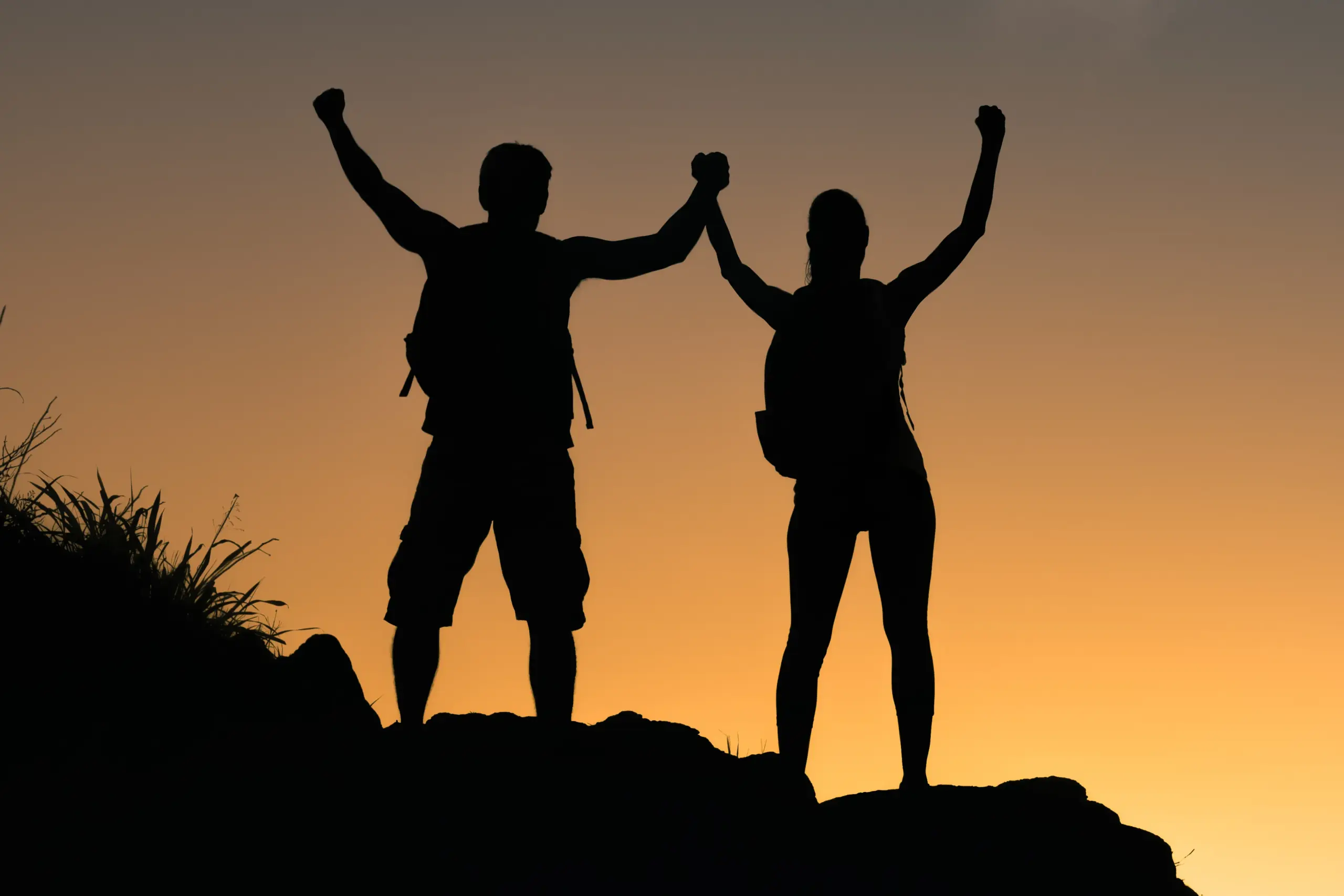 Weight-Loss-IV-Therapy-Clinic A couple completing a mountain climb hold their arms up to the sunset. Get IV therapy for weight loss from Delara Tavakoli, M.D. of Tavicare in Chevy Chase.